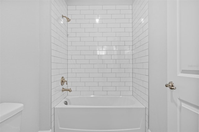 bathroom with tiled shower / bath combo and toilet