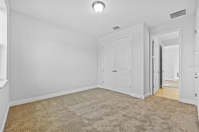 unfurnished bedroom featuring light colored carpet and a closet