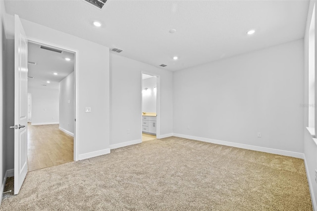 unfurnished bedroom featuring light colored carpet and connected bathroom