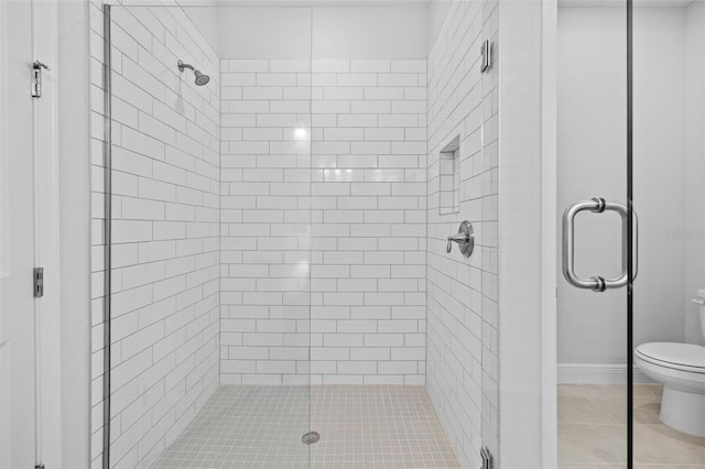 bathroom with tile patterned floors, toilet, and a shower with shower door