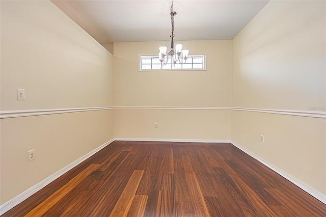 spare room featuring a notable chandelier and dark hardwood / wood-style flooring