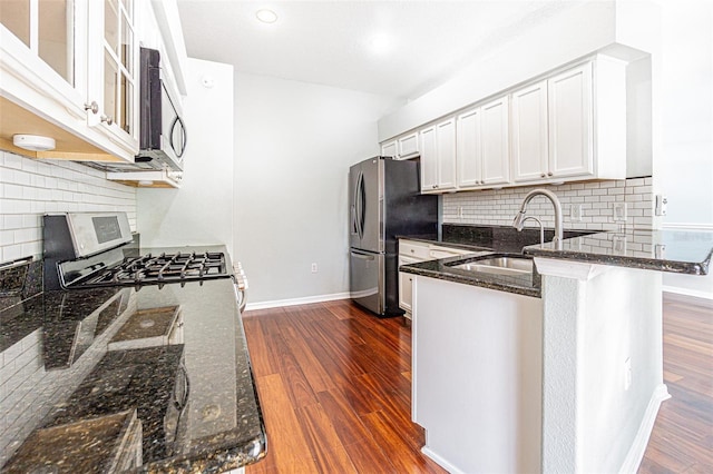 kitchen featuring dark hardwood / wood-style floors, dark stone countertops, sink, stainless steel appliances, and white cabinets