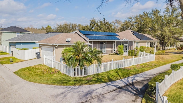 single story home featuring a front yard, a garage, a sunroom, and solar panels