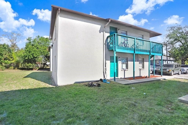 rear view of house featuring a lawn and a balcony