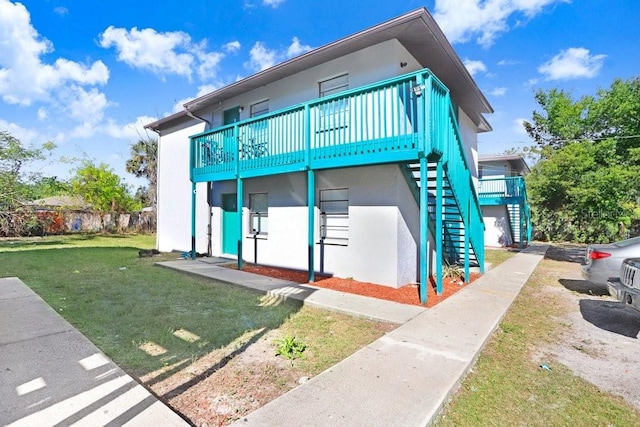 rear view of house featuring a lawn and a wooden deck