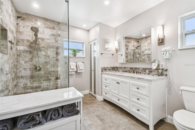 bathroom featuring toilet, a stall shower, vanity, and baseboards