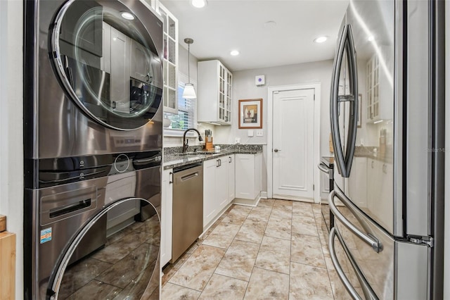 kitchen with stacked washer / drying machine, hanging light fixtures, appliances with stainless steel finishes, glass insert cabinets, and white cabinetry