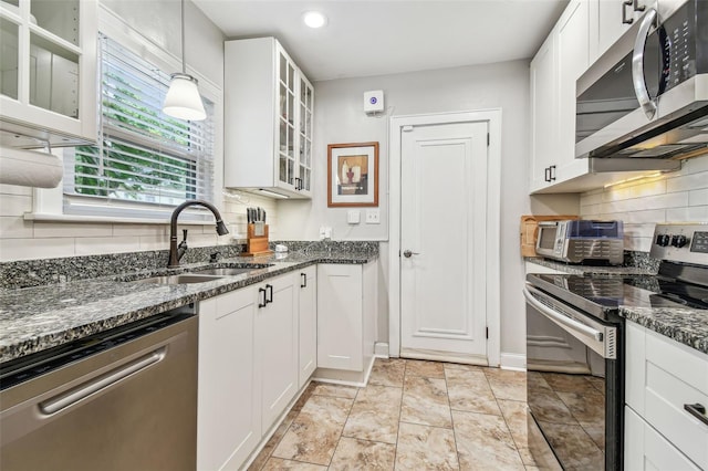 kitchen featuring decorative light fixtures, stainless steel appliances, a sink, white cabinetry, and glass insert cabinets