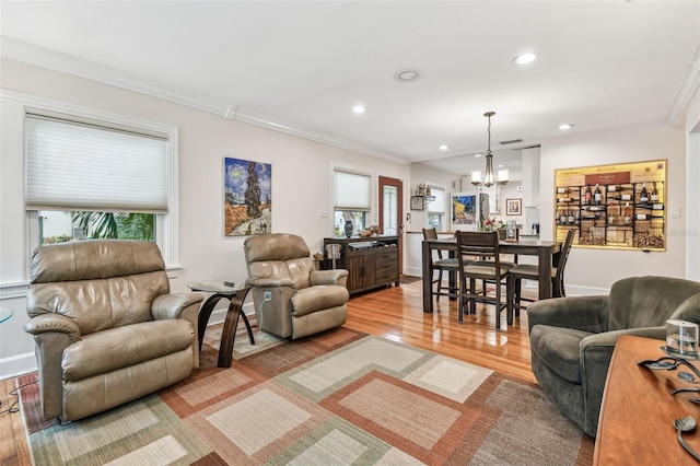 living area featuring light wood-style flooring, ornamental molding, a notable chandelier, and recessed lighting