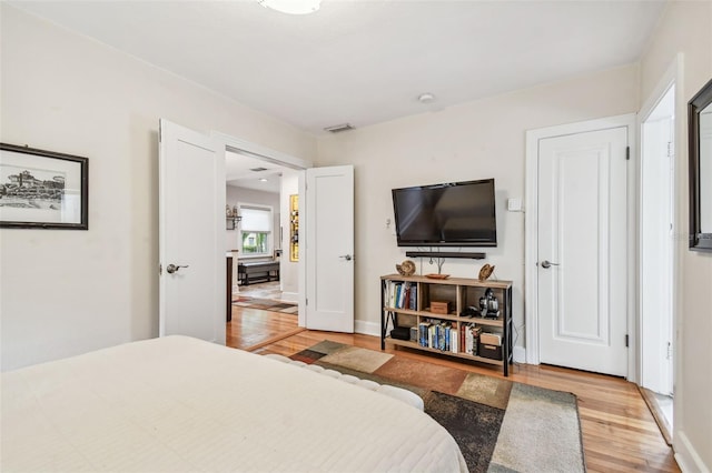 bedroom featuring visible vents, light wood-style flooring, and baseboards