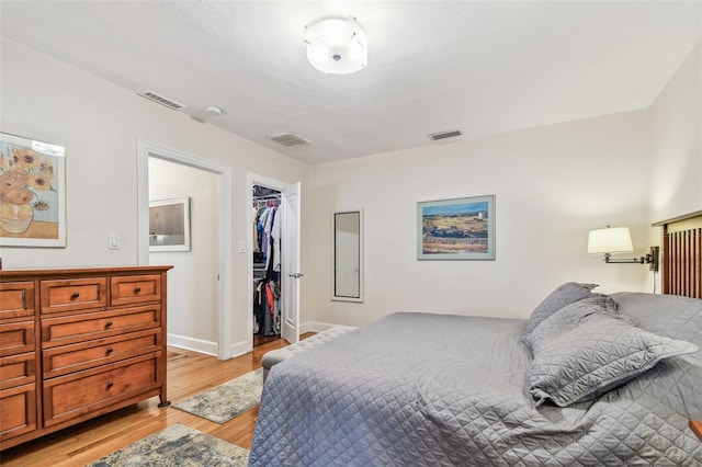 bedroom with visible vents, light wood-style flooring, baseboards, and a spacious closet