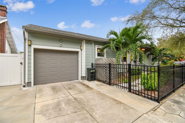 ranch-style house with driveway, a fenced front yard, and a garage