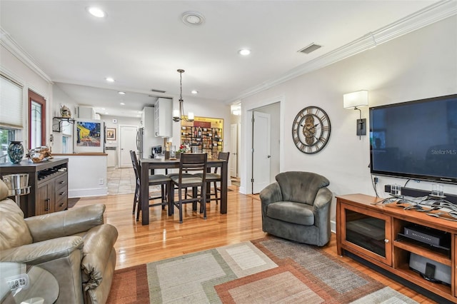 living room with light wood-type flooring, visible vents, crown molding, and recessed lighting