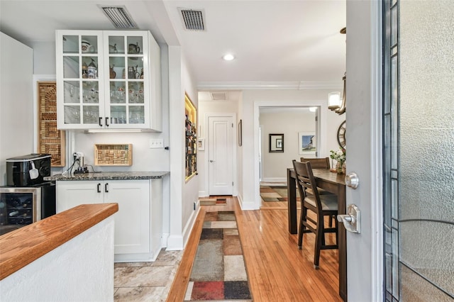 bar featuring pendant lighting, beverage cooler, visible vents, and ornamental molding