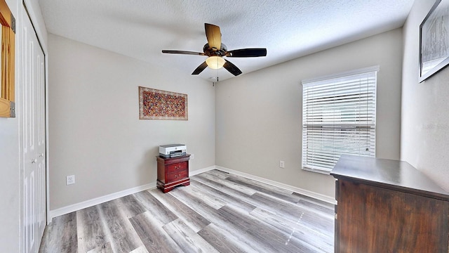 interior space featuring ceiling fan, a textured ceiling, and light hardwood / wood-style flooring