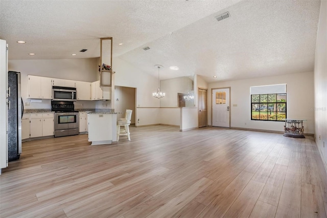 kitchen with appliances with stainless steel finishes, a textured ceiling, decorative light fixtures, light hardwood / wood-style flooring, and white cabinetry