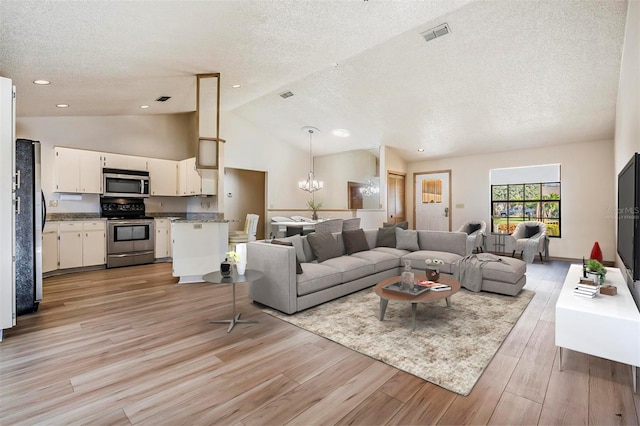 living room with a chandelier, a textured ceiling, high vaulted ceiling, and light hardwood / wood-style flooring