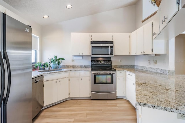 kitchen featuring light stone counters, sink, white cabinetry, and stainless steel appliances