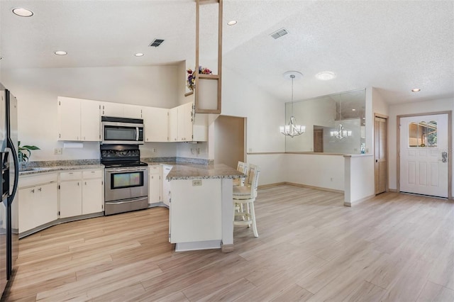 kitchen with stainless steel appliances, vaulted ceiling, a kitchen bar, and light stone countertops