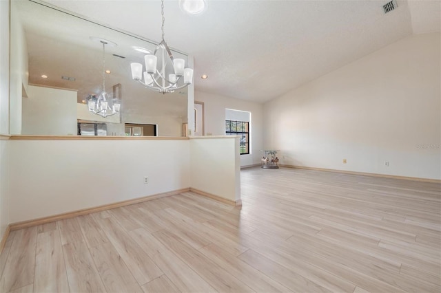 unfurnished room featuring vaulted ceiling, a chandelier, and light hardwood / wood-style flooring