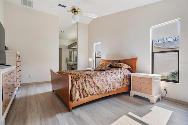 bedroom featuring ensuite bath, light hardwood / wood-style floors, vaulted ceiling, and ceiling fan