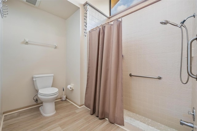 bathroom featuring wood-type flooring, toilet, and a shower with shower curtain