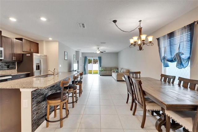 tiled dining area with ceiling fan with notable chandelier and sink