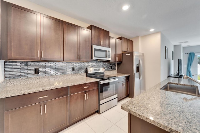 kitchen featuring light stone countertops, appliances with stainless steel finishes, tasteful backsplash, and sink