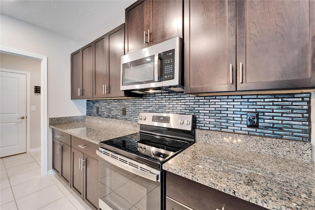 kitchen featuring light stone countertops, appliances with stainless steel finishes, tasteful backsplash, dark brown cabinets, and light tile patterned flooring