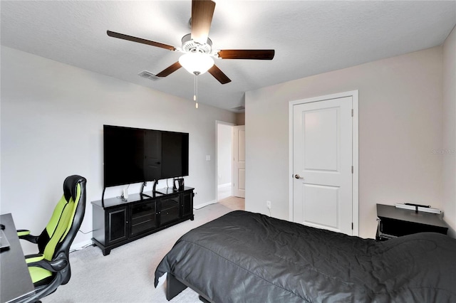 bedroom with ceiling fan, light colored carpet, and a textured ceiling