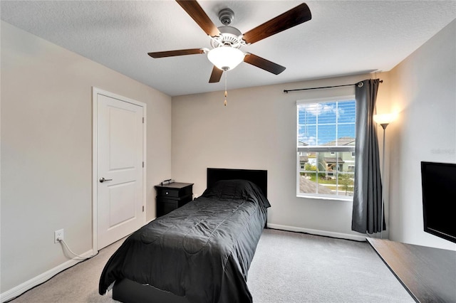 bedroom featuring a textured ceiling, light colored carpet, and ceiling fan