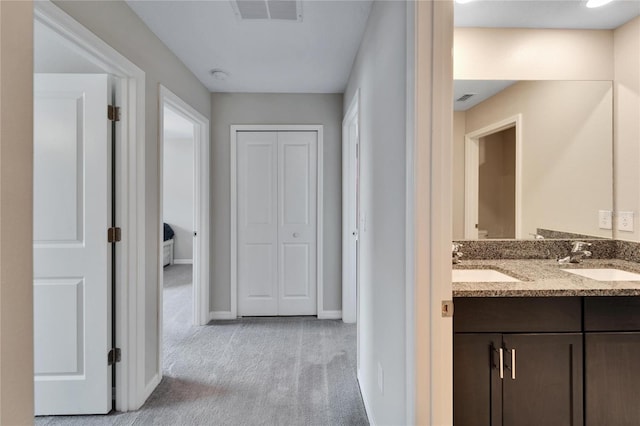 hall featuring light colored carpet and sink