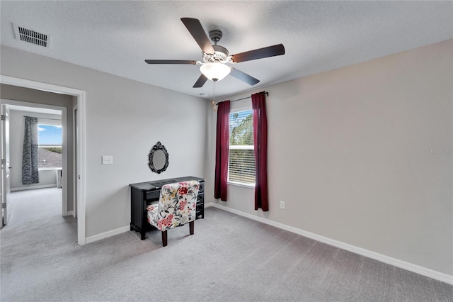 sitting room with light carpet, ceiling fan, and a textured ceiling