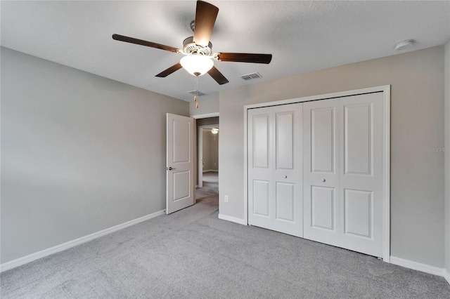 unfurnished bedroom featuring ceiling fan, a closet, and light carpet