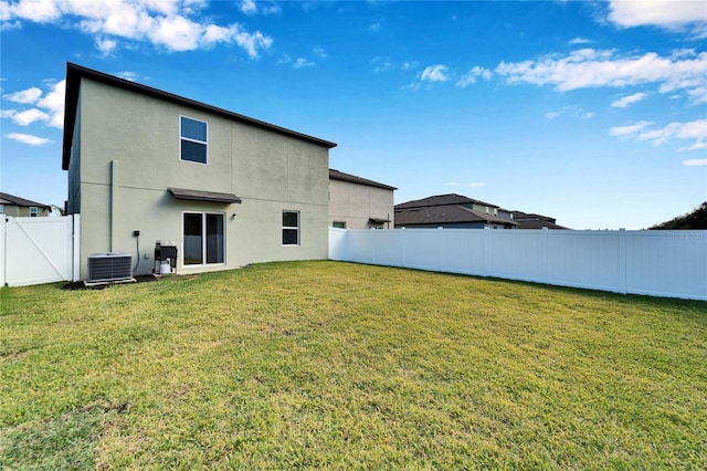 rear view of property featuring cooling unit and a yard