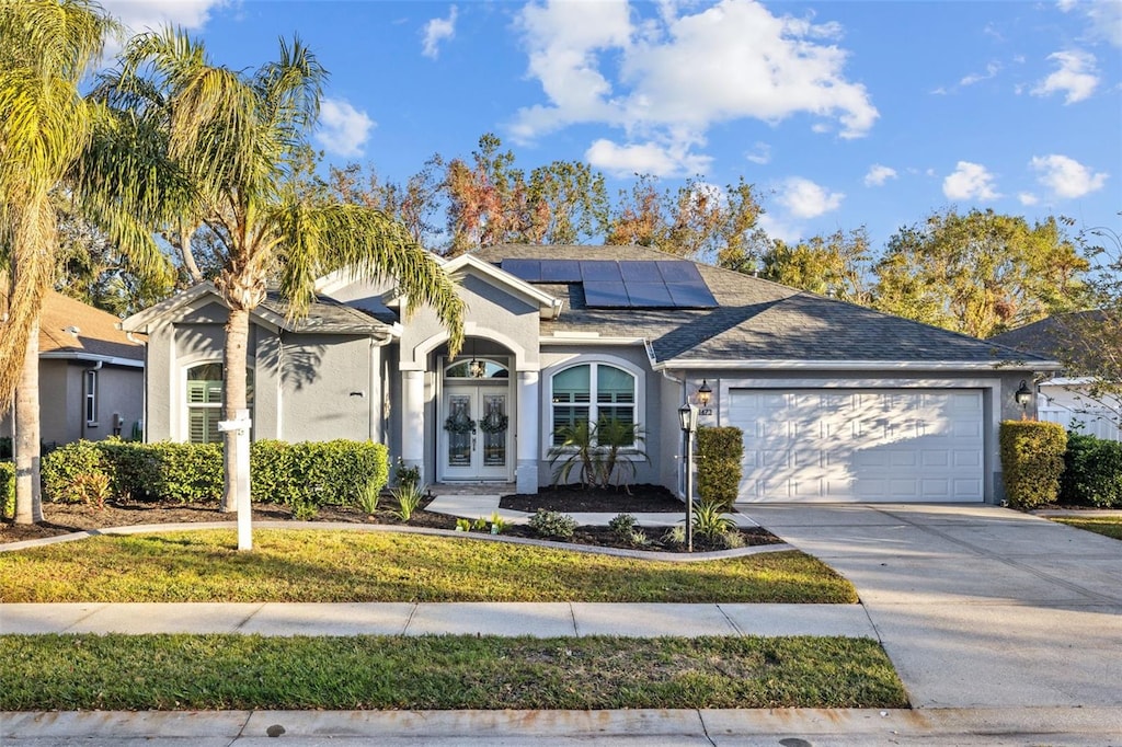 single story home featuring french doors, a garage, and solar panels