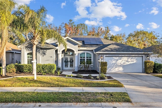 single story home featuring french doors, a garage, and solar panels