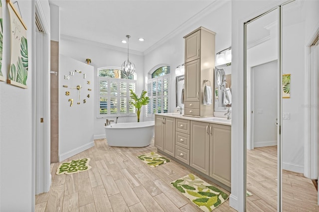 bathroom featuring a bathing tub, vanity, a chandelier, and ornamental molding