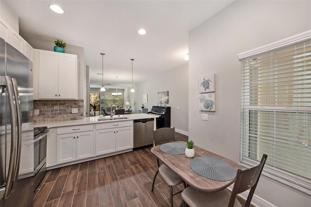 kitchen featuring sink, white cabinets, pendant lighting, and appliances with stainless steel finishes