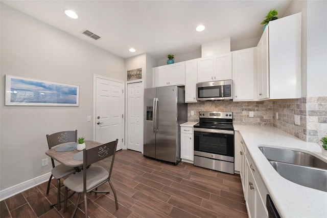 kitchen featuring stainless steel appliances, white cabinetry, tasteful backsplash, and sink