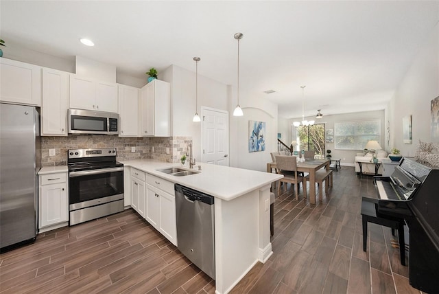 kitchen featuring sink, white cabinets, stainless steel appliances, and decorative light fixtures