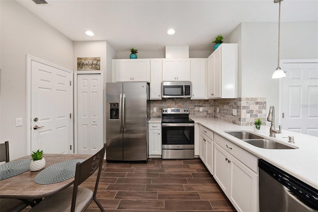 kitchen with decorative light fixtures, white cabinetry, sink, and appliances with stainless steel finishes