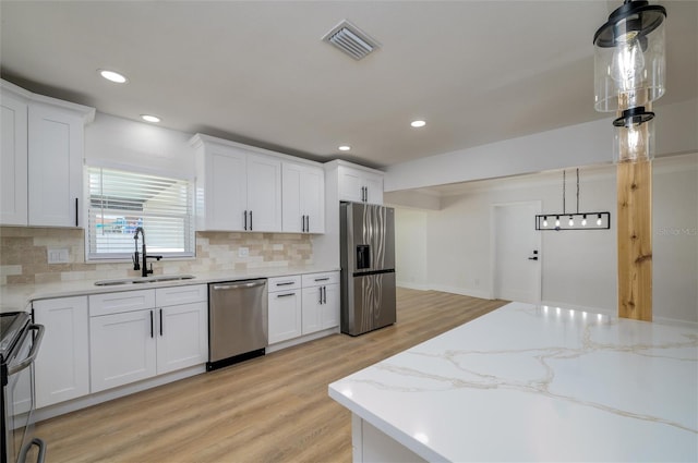 kitchen featuring decorative light fixtures, sink, white cabinetry, and stainless steel appliances