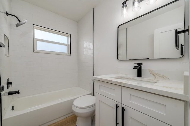 full bathroom with vanity, hardwood / wood-style flooring, toilet, and tiled shower / bath