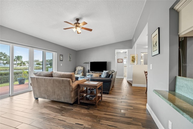 living room with lofted ceiling, ceiling fan, dark hardwood / wood-style flooring, and a textured ceiling