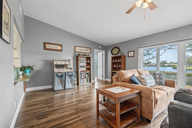 living room featuring dark hardwood / wood-style flooring, a textured ceiling, vaulted ceiling, ceiling fan, and a water view