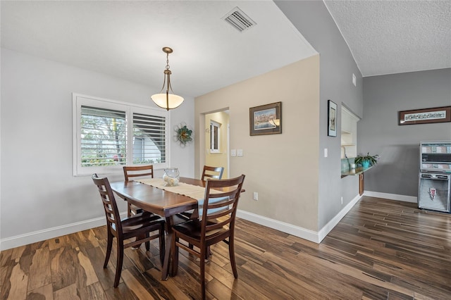 dining space featuring a textured ceiling, lofted ceiling, and dark hardwood / wood-style floors