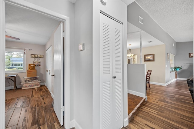 hallway with dark hardwood / wood-style flooring and a textured ceiling