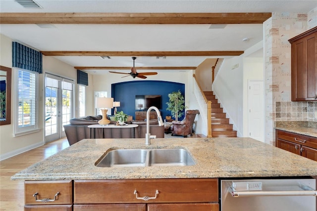 kitchen featuring light stone counters, beam ceiling, backsplash, and sink