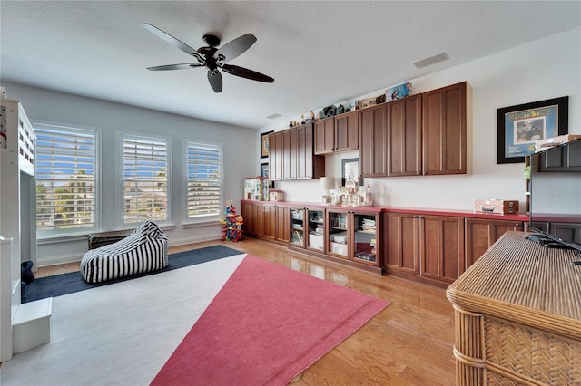 kitchen with a textured ceiling, ceiling fan, and light hardwood / wood-style floors